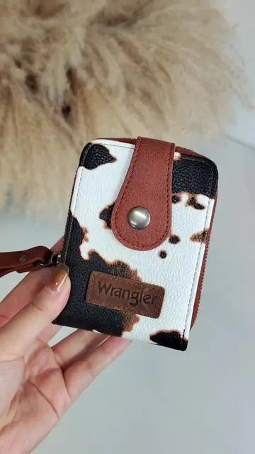 If you're looking for a unique and trendy wallet, check out this #wrangler piece! The cow print design is so chic and makes a bold statement. #OnTheGo #wranglerpurse 