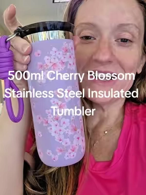 This 500ml stainless steel insulated tumbler features a cherry blossom design, double-wall insulation, and a convenient carrying strap for hot or cold drinks on the go. #CherryBlossom #TravelMug #InsulatedTumbler #CoffeeCup #WaterBottle